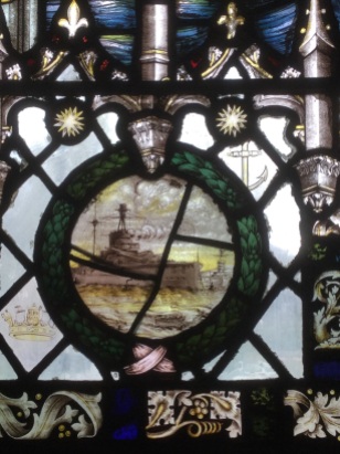 Detail of stained glass window showing a ship in a battle at sea.