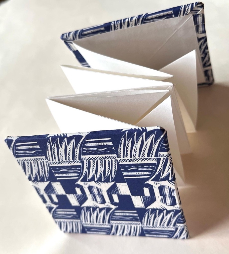 A small folded book with covers using decorative paper printed with an Enid Marx design in dark blue.
