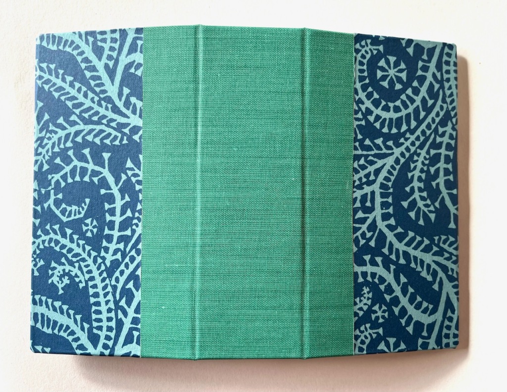 The covers of the blue, turquoise and green Chinese thread book.